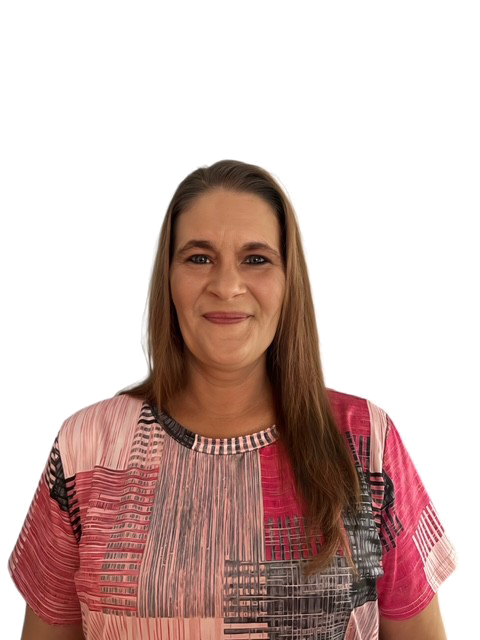 A person is smiling, wearing a colorful patterned shirt, and standing against a plain background.