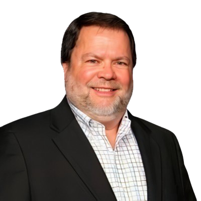 A smiling man with a beard is wearing a dark suit jacket over a checkered shirt against a gray background.