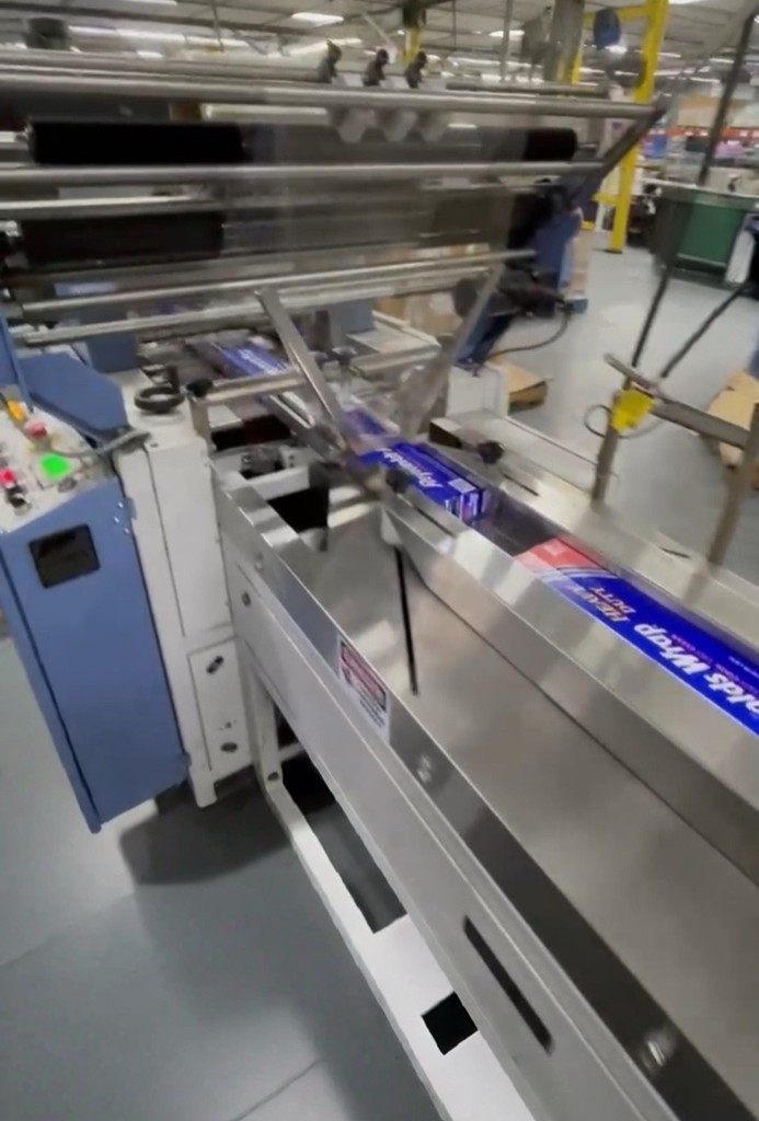 A packaging machine is in operation with conveyor belts moving products for processing.