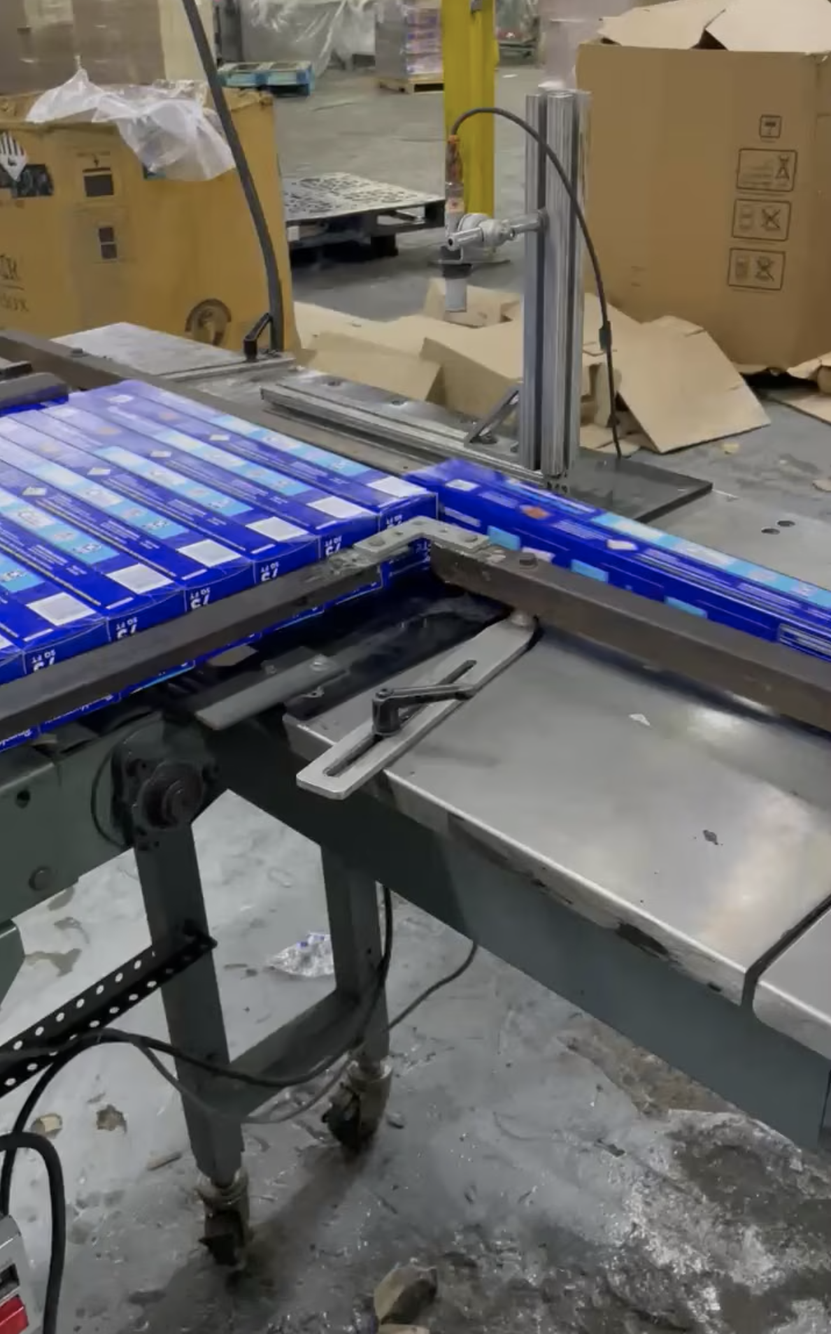 A conveyor belt system quickly transfers blue boxes along a metal assembly line.