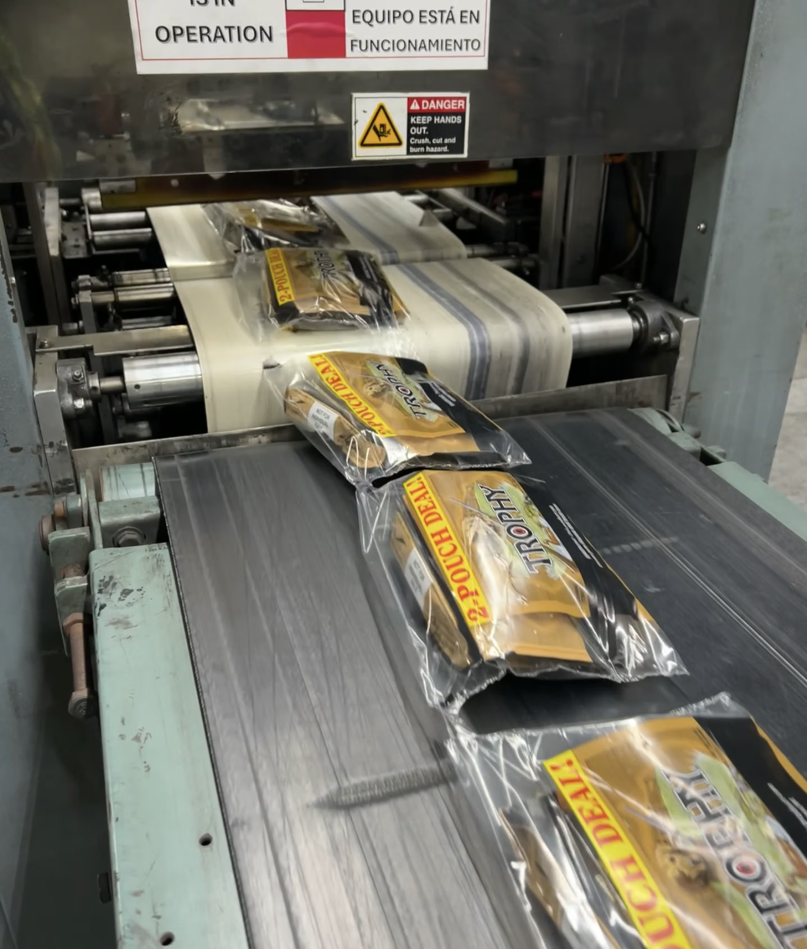 A packaging machine processes and seals packets of pretzels, moving them along a conveyor belt.